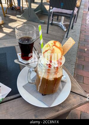 Caffè ghiacciato con una palla di gelato alla vaniglia sul gelato e salsa di fragole Foto Stock