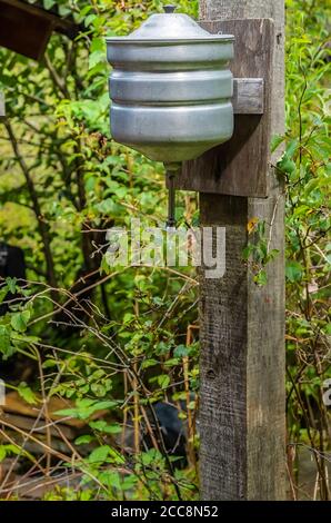 un vecchio lavabo manuale in alluminio pende su un legno bar nel giardino di un terreno suburbano Foto Stock