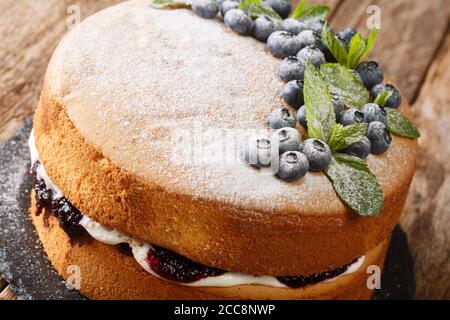 La ricetta della torta di Spagna Victoria combina la marmellata di mirtilli e la crema di chiocciole sulla tavola di ardesia sul tavolo. Orizzontale Foto Stock