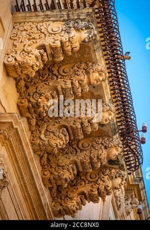 Riccamente intagliato balcone in pietra sul barocco Palazzo Villadorata a Noto, a sud della Sicilia Orientale Foto Stock