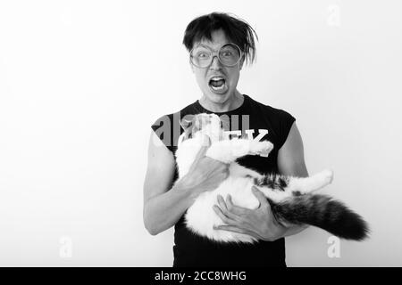 Studio girato di giovane uomo nerd che guarda eccitato mentre tiene gatto  carino e occhiali da vista Foto stock - Alamy
