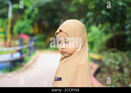 Una bella bambina musulmana indonesiana carina nel parco Foto Stock