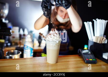 Barista Making frappe - caffè latte ghiacciato con caramello e sciroppo di cioccolato e panna montata. Immagine sfocata, messa a fuoco selettiva Foto Stock