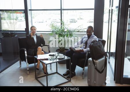 Giorno della conferenza. Incontro di giovani partner d'affari prima di arrivare al punto finale del viaggio d'affari. Uomo e donna che lavorano con i gadget nella zona degli ospiti speciali. Concetto di business, finanza, annuncio. Foto Stock