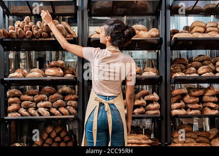 Giovane donna adulta in piedi vicino al pane appena sfornato Foto Stock