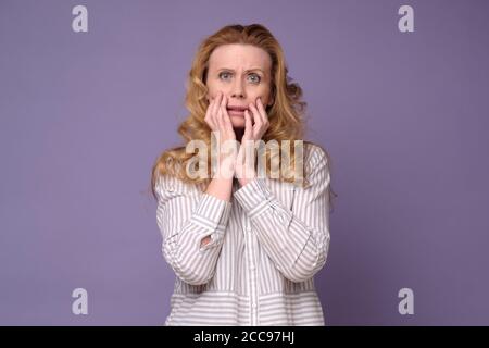 Scioccata donna matura copre la sua bocca con le mani sensazione di stress Foto Stock