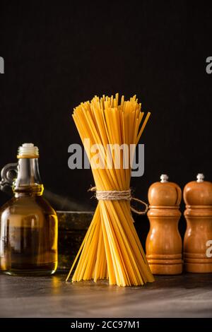 Spaghetti italiani non cotti con olio d'oliva e condimenti isolati nero Foto Stock