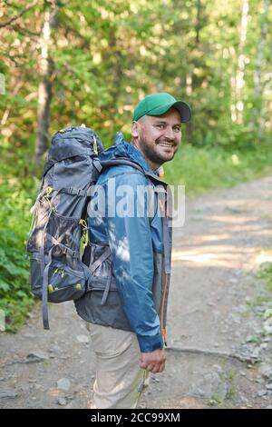 Ritratto di uomo maturo con zaino sorridente alla fotocamera mentre escursioni nella foresta Foto Stock