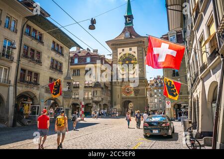 Berna Svizzera , 27 giugno 2020 : Vista vecchia strada con bandiere turistiche e torre dell'orologio Zytglogge in via Kramgasse nel centro storico di Berna Svizzera Foto Stock