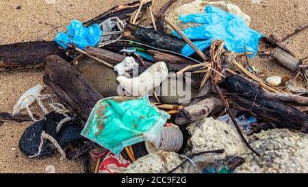 Rifiuti medici, maschere e guanti di plastica spazzatura rifiuti sulla riva del mare. Coronavirus covid-19 inquinamento malattia l'ambiente. Usato maschera chirurgica blu Th Foto Stock