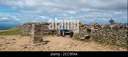 Due escursionisti seduti per ammirare la vista dal rifugio sulla cima di Pen-y-Ghent, una delle tre vette dello Yorkshire Foto Stock