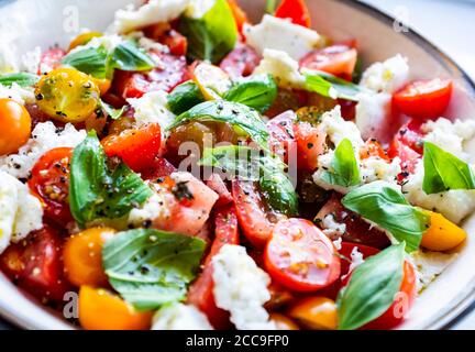 Insalata caprese fatta in casa insalata tradizionale italiana di Capri a base di pomodori freschi , mozzarella di bufala con foglie di basilico e olive vergini Foto Stock