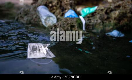 Rifiuti medici, maschere, bottiglie di plastica e guanti rifiuti rifiuti di acqua di mare. Coronavirus covid-19 inquinamento malattia l'ambiente. Maschera chirurgica usata Foto Stock