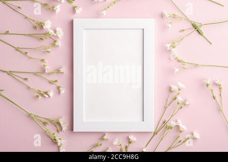 Bianco mockup cornice foto vuota con mouse-orecchio fiori di ceci su sfondo rosa, vista dall'alto spazio copia Foto Stock