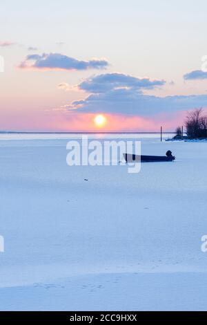 Barca in una baia ghiacciata di Fehmarn suono al tramonto Foto Stock