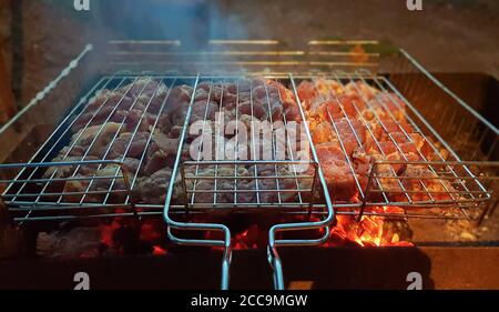 Il processo di cottura del kebab sulla griglia. La carne succosa e fragrante langue al fuoco e al fumo. Concetto di picnic di campagna di notte. Appetitoso Foto Stock