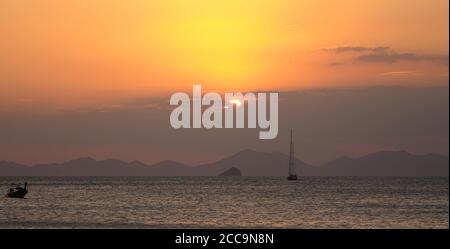 Tramonto sull'oceano con cielo arancione alla spiaggia di Phra nang a Railay, Krabi, Thailandia. Foto Stock