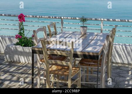 CHALKIDIKI, Grecia taverna vuota sedie di legno e tavolo dopo nuove misure covid-19. Ristorante all'aperto con area salotto vicino al mare senza clienti. Foto Stock