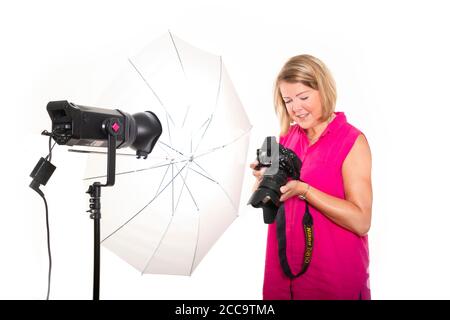 Ritratto orizzontale di un fotografo che controlla le foto sul retro di una fotocamera digitale mentre lavora in uno studio. Foto Stock