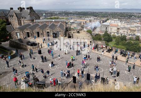 I visitatori del Castello di Edimburgo si levano socialmente distanziati in circoli distinti mentre guardano la cerimonia delle armi una o'clock mentre la Scozia continua nella fase 3 delle restrizioni di blocco del coronavirus. Foto Stock