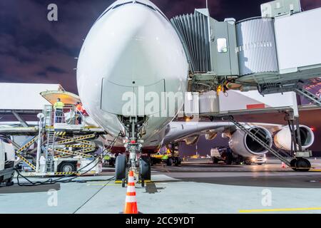 Un enorme aereo parcheggiato accanto al terminal passeggeri su mezzanotte prima della partenza del volo Foto Stock