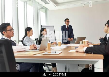 dirigente aziendale asiatico che facilita una discussione durante la riunione di gruppo in ufficio Foto Stock