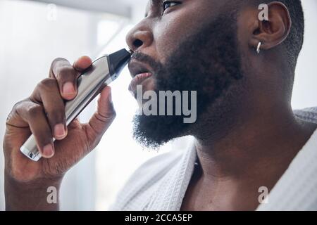 Foto messa a fuoco sulla mano maschio che tiene il rifinitore Foto Stock