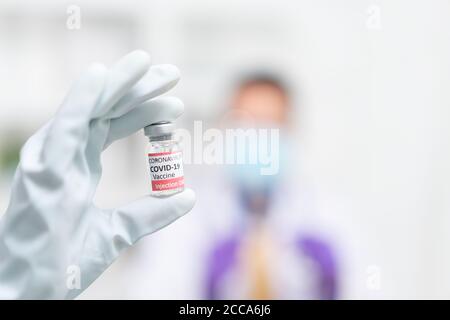 Sviluppo e creazione di un vaccino del coronavirus COVID-19. Concetto di vaccino del Coronavirus in mano di giara del vaccino blu medico. Concetto di vaccino della lotta A. Foto Stock