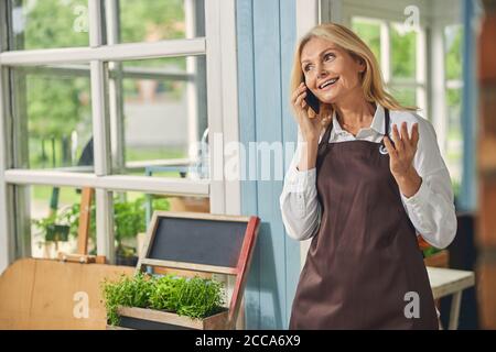 Donna sorridente e attraente che parla sullo smartphone Foto Stock