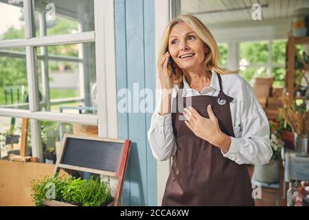 Donna matura e contenta che chiacchiera sullo smartphone Foto Stock