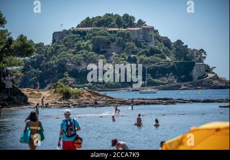 Bormes Les Mimosas, Francia. 20 Agosto 2020. I bagnanti sono sulla spiaggia sotto la residenza estiva del capo di stato, di Francia, Macron, il Fort de Bregancon. L'ex forte si trova su una roccia sulla costa mediterranea vicino Tolone. Credit: Michael Kappeler/dpa/Alamy Live News Foto Stock