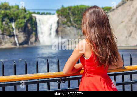 Quebec città turistica donna a Chute montmorency cade quebec popolare attrazione. Giovane donna in abito estivo rosso che guarda le cascate Foto Stock