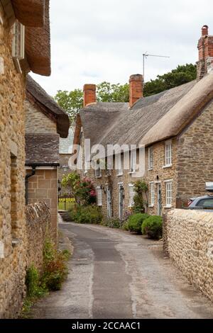 Tradizionali case con tetto in paglia nel bellissimo villaggio di Burton Bradstock, Dorset, Inghilterra. Foto Stock