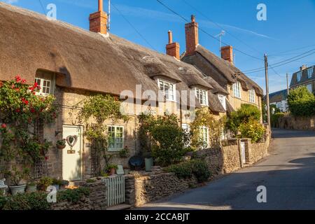 Tradizionali case con tetto in paglia nel bellissimo villaggio di Burton Bradstock, Dorset, Inghilterra. Foto Stock