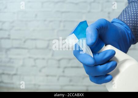 indossare guanti di gomma blu per il flacone spray Foto Stock