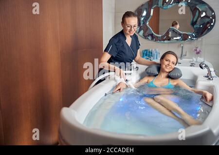 Donna sorridente terapeuta che esegue una procedura balneologica Foto Stock