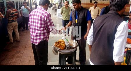 DISTRETTO KATNI, INDIA - 15 SETTEMBRE 2019: Fornitore asiatico di cibo di strada che dà samosa al cliente alla stazione ferroviaria. Foto Stock