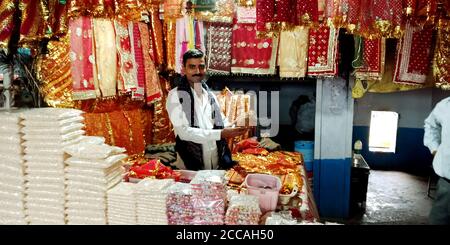DISTRETTO SATNA, CITTÀ di MAIHAR, INDIA - 12 SETTEMBRE 2019: La gente tradizionale indù che vende i beni religiosi al deposito di offerta della via del tempio. Foto Stock