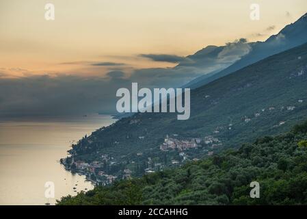 Nuvole colorate e frastagliate sul Monte Baldo e sull'estremità settentrionale e sulla sponda orientale del Lago di Garda all'alba, Veneto, Trentino, Italia Foto Stock