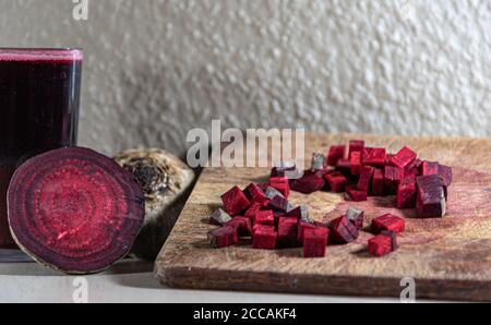 Barbabietola (Beta vulgaris L.) tagliata su una tavola di legno accanto a tuberi rotti. Verdure per insalate. Verdure usate nella cucina brasiliana. Fonte di zucchero pr Foto Stock