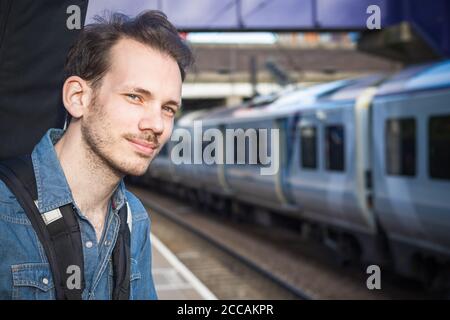 Ritratto di un giovane caucasico in attesa di treno piattaforma Foto Stock