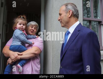 Un Taoiseach Micheal Martin chiacchiera con la gente del posto insieme al piccolo bambino mia Thornton mentre visita le case e le aziende danneggiate dall'alluvione di Skibbereen la mattina dopo un'inondazione ha causato danni estesi ad un certo numero di locali nella popolare città turistica irlandese. Foto Stock