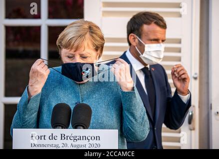 Bormes Les Mimosas, Francia. 20 Agosto 2020. Emmanuel Macron, presidente della Francia, si trova dietro la cancelliera tedesca Angela Merkel (CDU) alla conferenza stampa nella residenza estiva del Capo di Stato, il Forte di Bregancon. L'ex fortezza si trova su una roccia sulla costa mediterranea vicino Tolone. Credit: Michael Kappeler/dpa/Alamy Live News Foto Stock