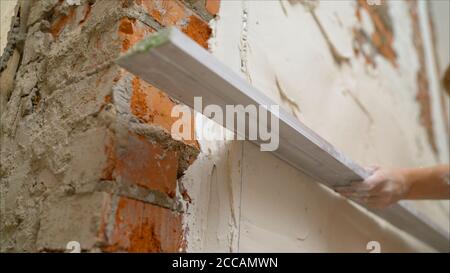 Lo strumento Provila viene applicato alla parete. La soluzione viene applicata alla parete con un attrezzo speciale. Lavoratore applicato con una spatola a una soluzione di Foto Stock
