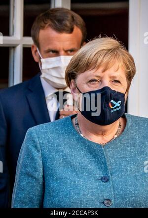 Bormes Les Mimosas, Francia. 20 Agosto 2020. Emmanuel Macron, presidente della Francia, si trova dietro la cancelliera tedesca Angela Merkel (CDU) alla conferenza stampa nella residenza estiva del Capo di Stato, il Forte di Bregancon. L'ex fortezza si trova su una roccia sulla costa mediterranea vicino Tolone. Credit: Michael Kappeler/dpa/Alamy Live News Foto Stock