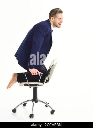 Il ragazzo in tuta da ufficio si diverte durante la pausa caffè. Manager si muove sulla sua sedia e gode di successo. Felice giovane uomo d'affari in sedia isolato su sfondo bianco. Relax, pausa, business concept. Foto Stock