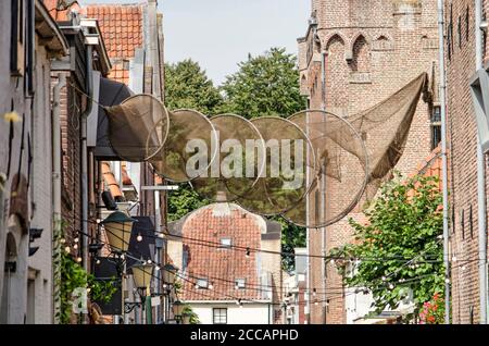 Elburg, Paesi Bassi, 30 luglio 2020: Rete da pesca sospesa in una strada del centro storico, come riferimento alla storia della città Foto Stock