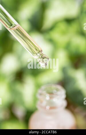 Goccia di liquido cosmetico che cade dalla pipetta. Foto Stock