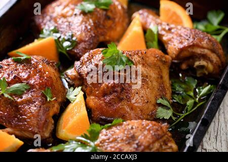 fette appetitose di pollo al forno con crosta fritta croccante e arance in una teglia Foto Stock