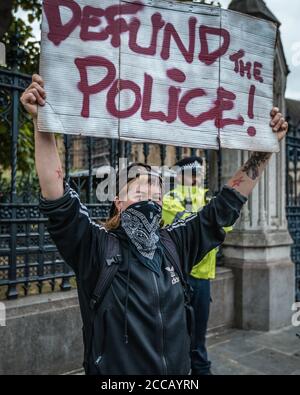 Il manifestante tiene il cartello "defund the police" al di fuori del parlamento dopo L'uccisione di George Floyd e durante il blocco pandemico Foto Stock